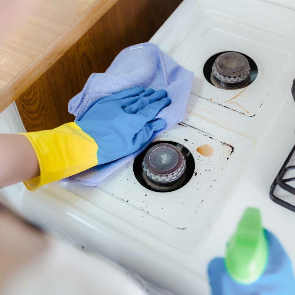 Employee cleaning stove top as part of kitchen deep cleaning by best cleaning service in Qatar